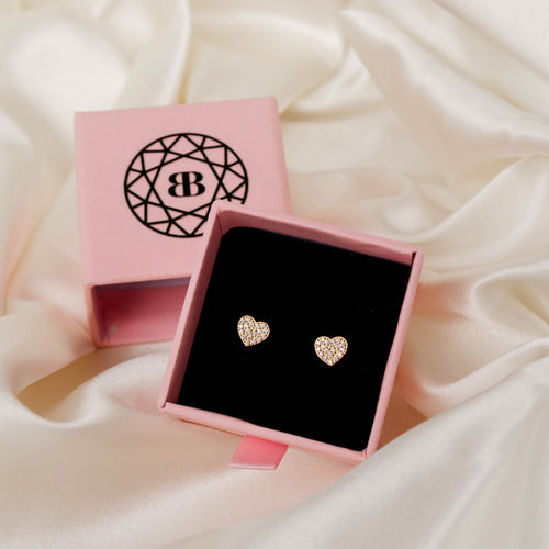Heart-shaped earrings in a pink box on a soft fabric background