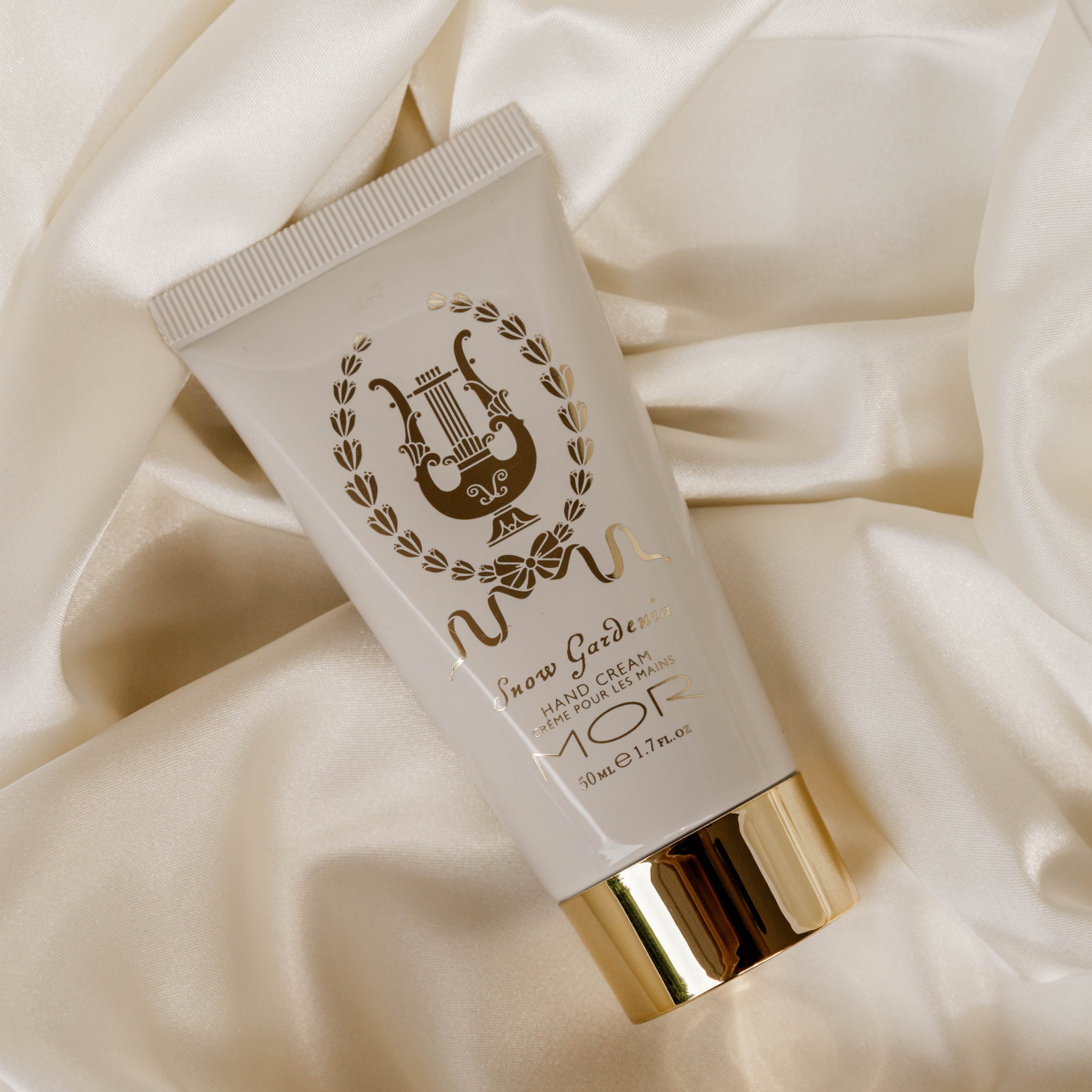 Tube of hand cream with gold cap on a soft beige fabric background