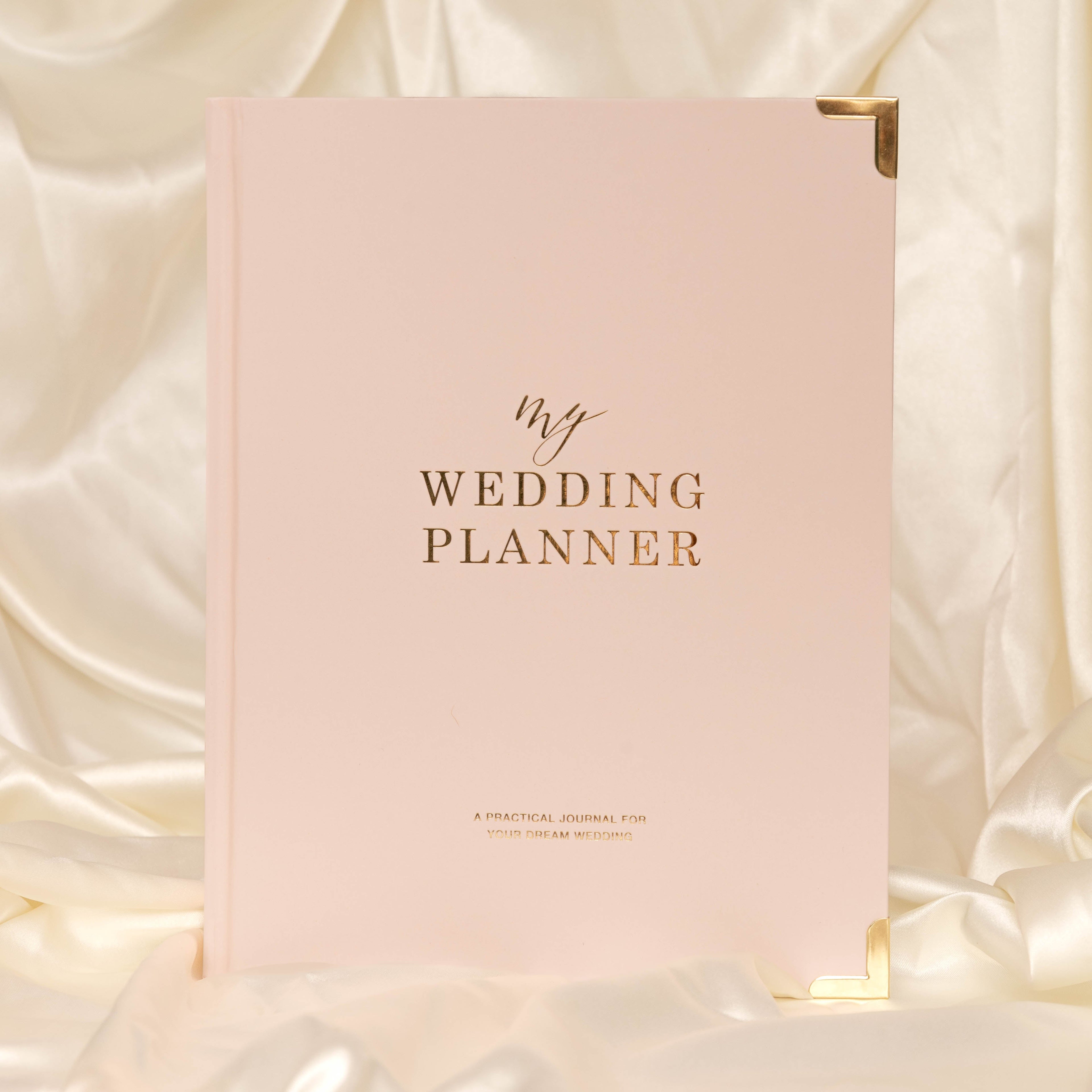 Pink wedding planner book on a soft, light-coloured fabric background