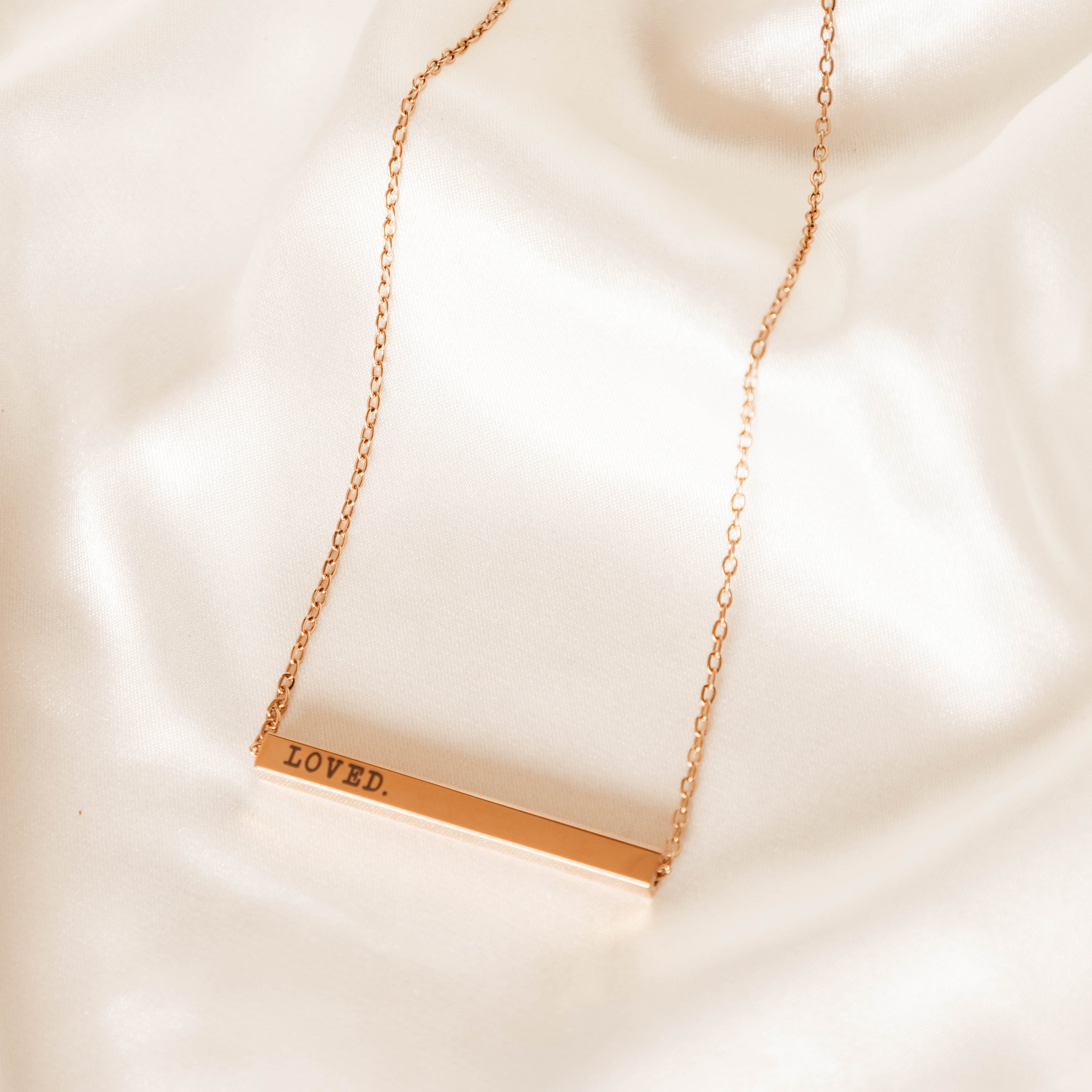 Gold necklace with a bar pendant on a soft beige background