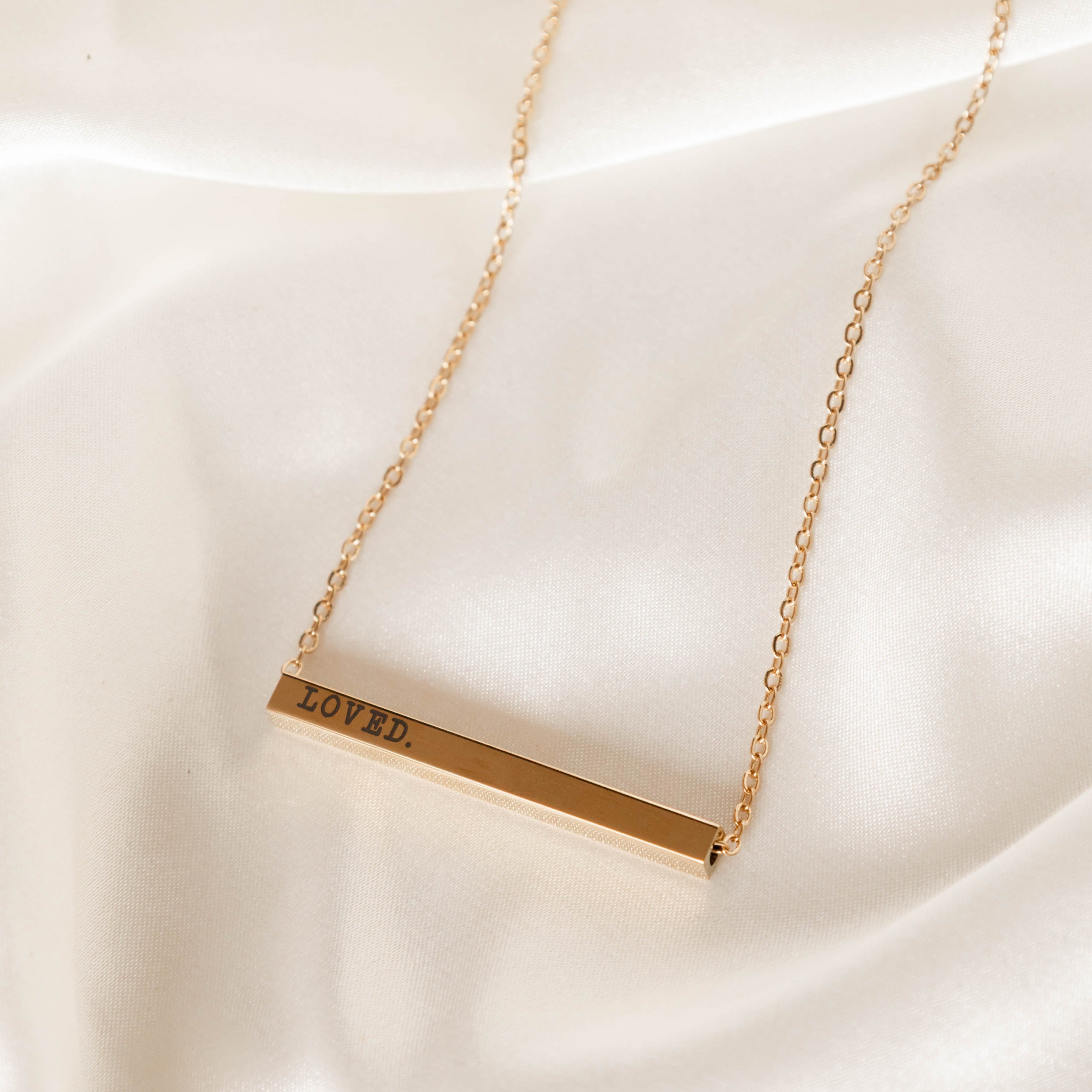Gold necklace with a bar pendant on a white background