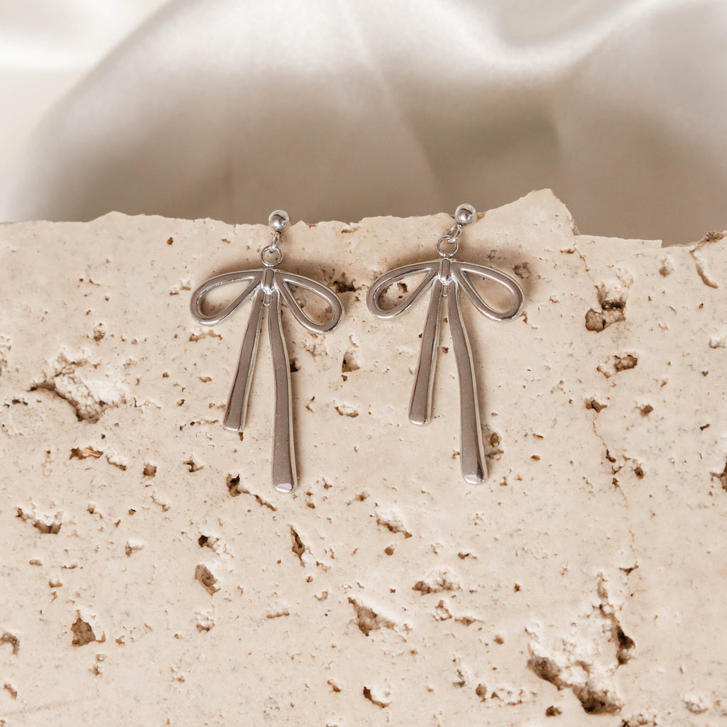 Silver earrings on a textured beige surface