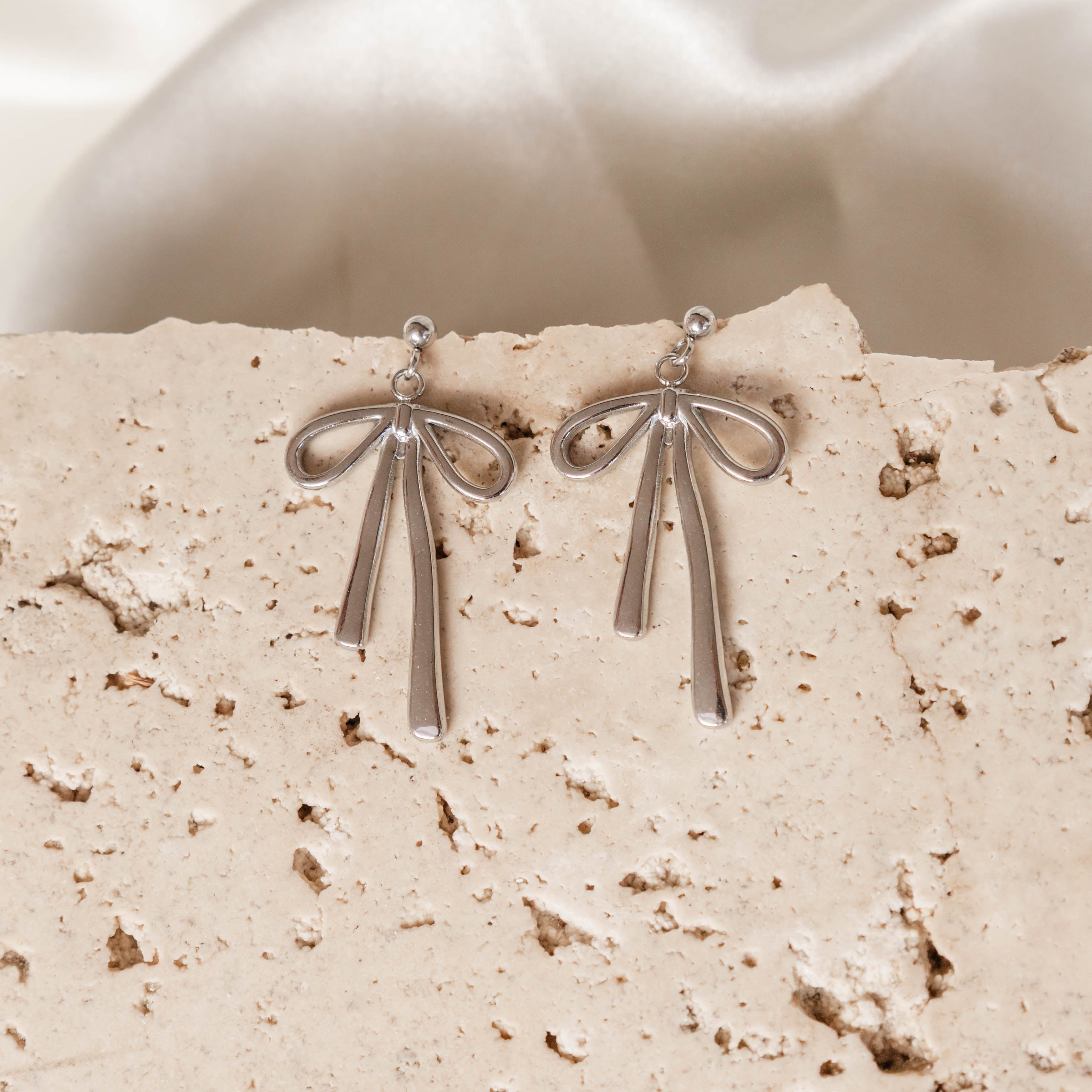 Silver earrings on a textured beige surface