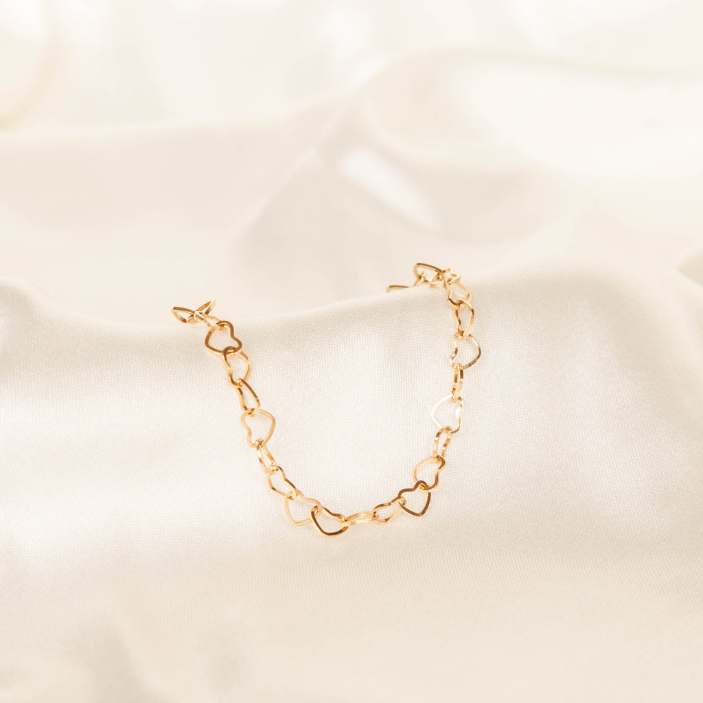 Gold chain bracelet on a beige fabric background