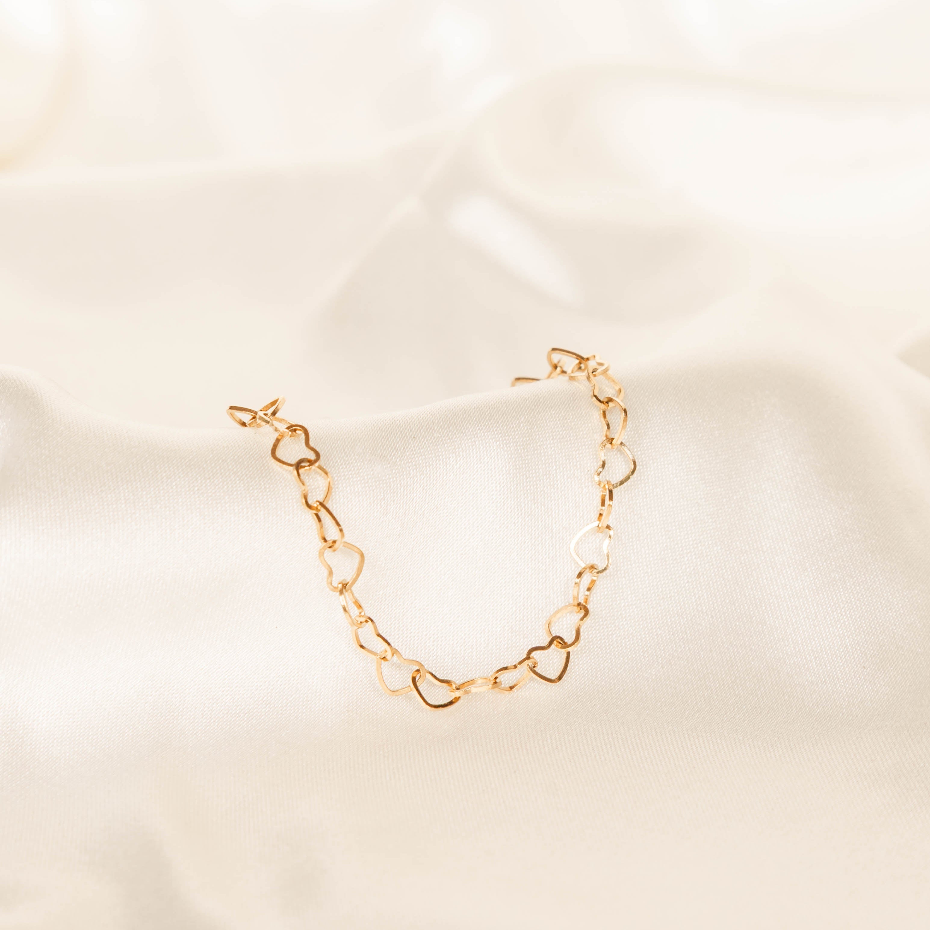 Gold chain bracelet on a beige fabric background
