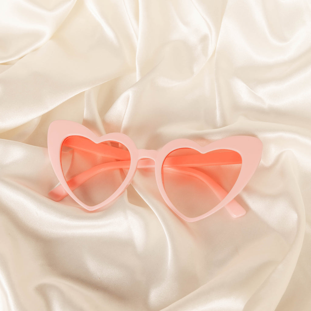 Heart-shaped sunglasses on a beige fabric background