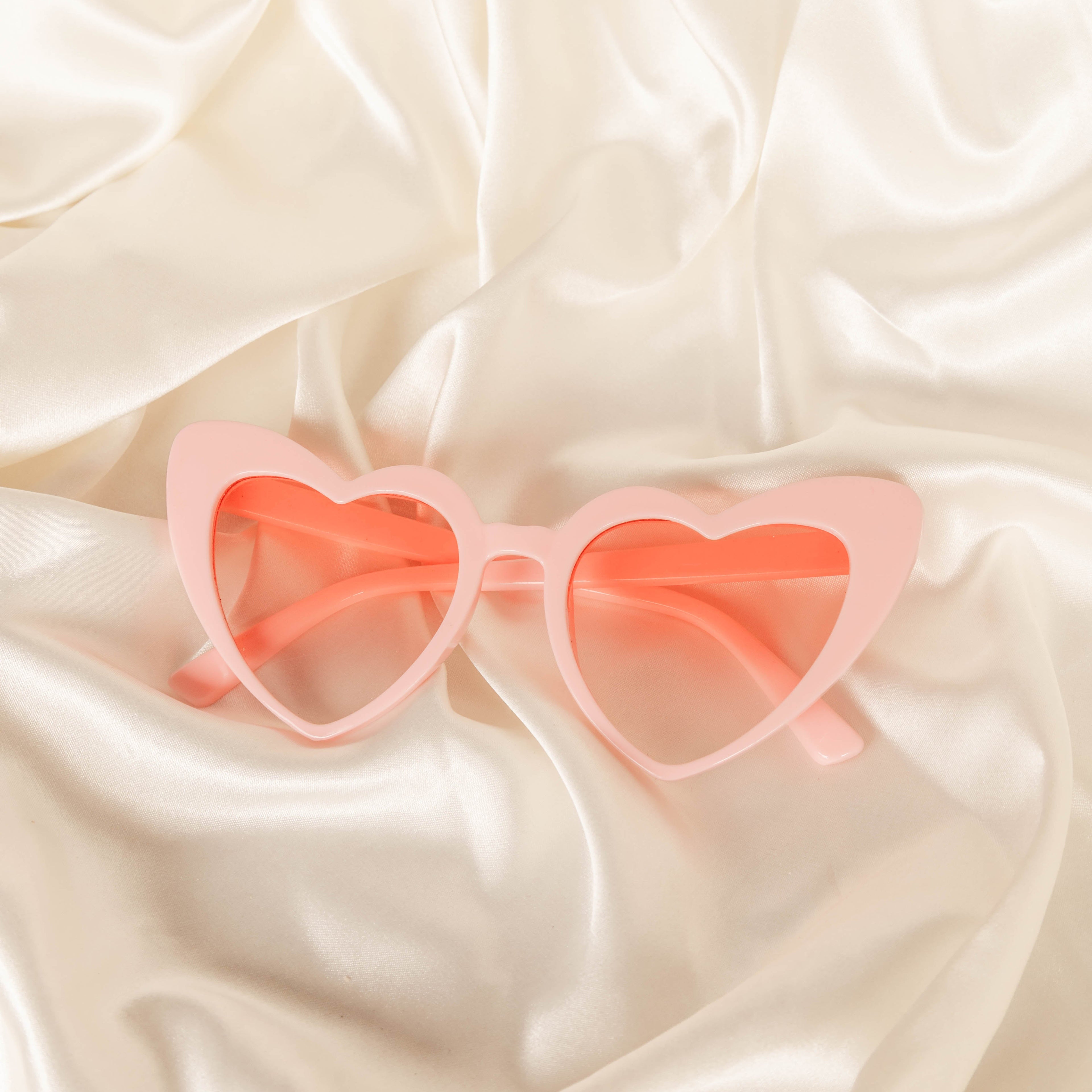 Heart-shaped sunglasses on a beige fabric background