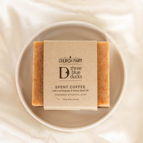 Bar of soap with a label on a white plate on a textured beige background