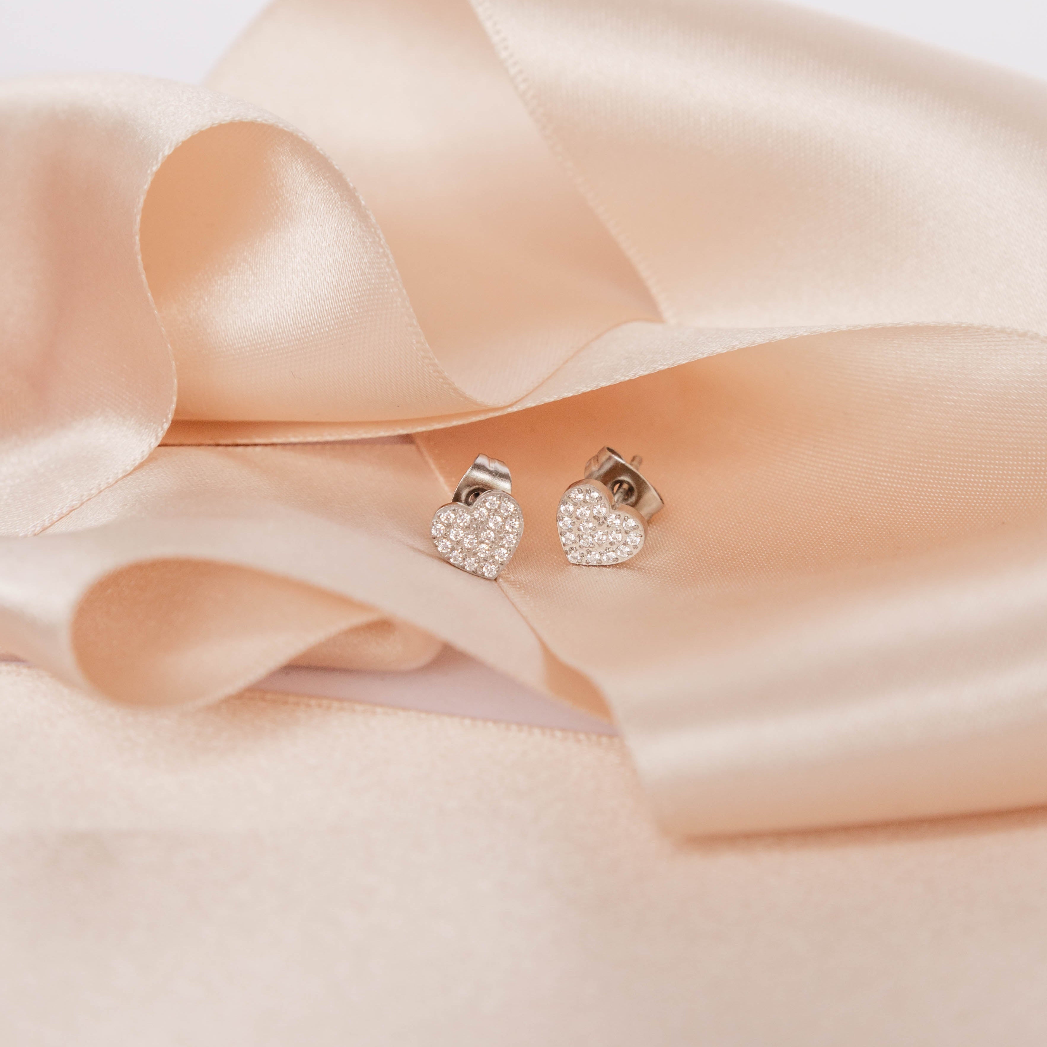 Pair of silver earrings on a soft pink satin ribbon