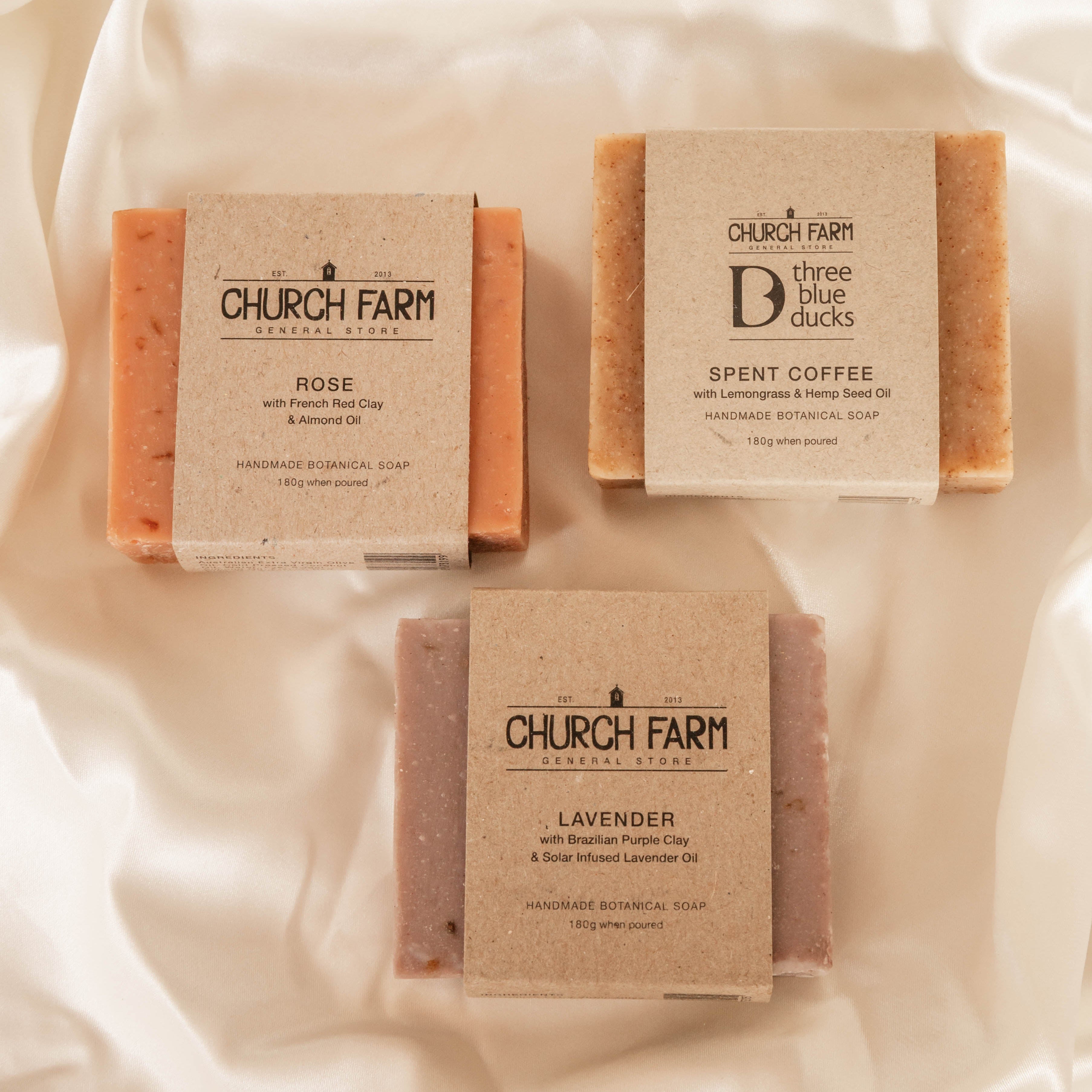 Three bars of Church Farm soap on a soft fabric background