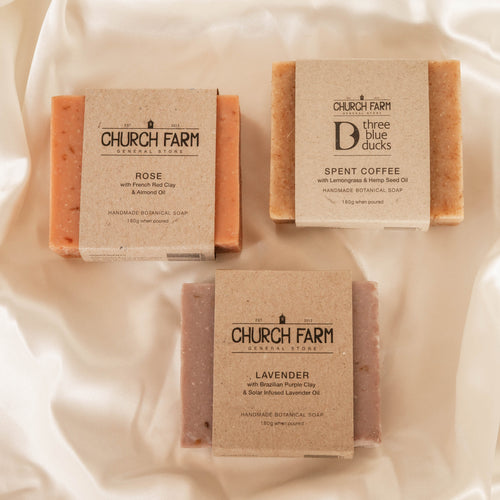 Three bars of Church Farm soap on a soft fabric background