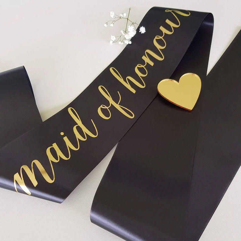 Black sash with gold 'maid of honour' text and heart design on a light background