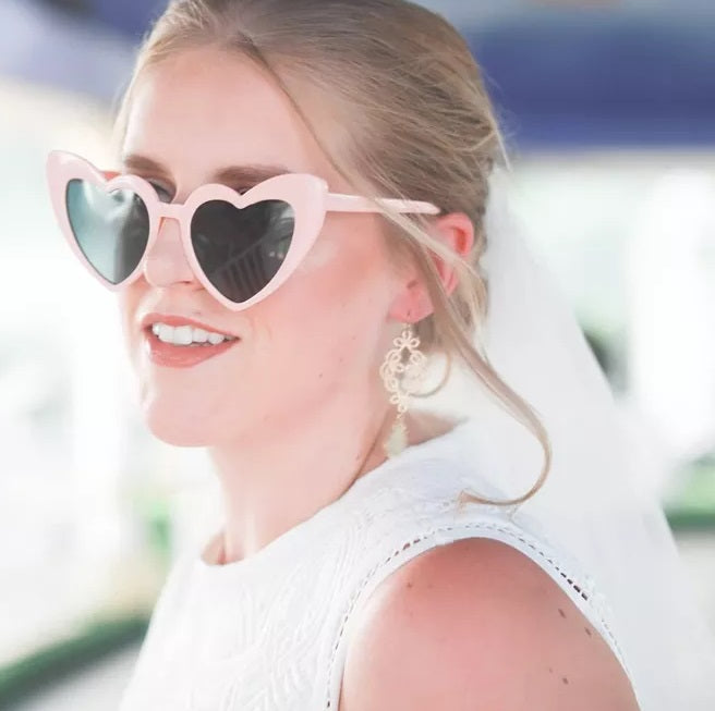 Woman wearing heart-shaped sunglasses with a blurred background