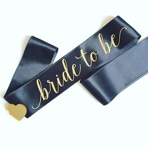 Black sash with 'bride to be' in gold letters on a white background