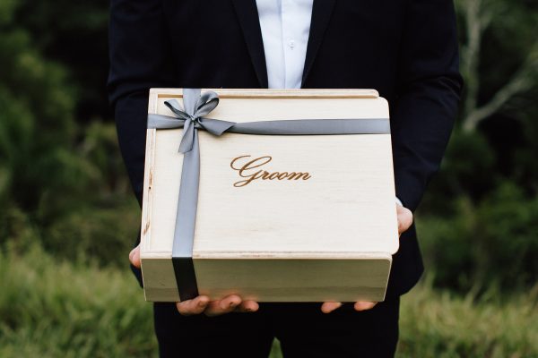groom holding wooden keepsake gift box engraved with 'groom' and finished with bridal grey ribbon