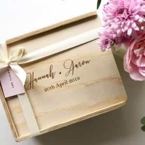 Custom engraved gift box engraved with couples names and their wedding date, finished with ivory ribbon and blush flowers surrounding