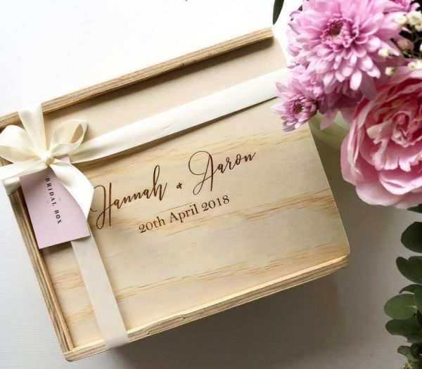 Custom engraved gift box engraved with couples names and their wedding date, finished with ivory ribbon and blush flowers surrounding