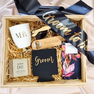 Groom to be gift hamper in a keepsake wooden gift box with a mug, groom to be sash, soap, chocolate, bottle opener, stubby cooler and sunnies