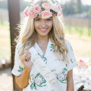 bride to be wearing a flower crown and protea robe with a bride to be party sash