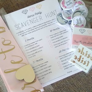 hens party supplies scattered including bridal party ribbon, bride tribe tattoos, bridal party badges, scavenger hunt party game