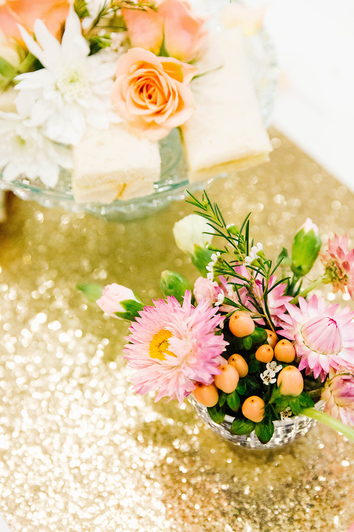 table decorated with gold sequen runner, high tea sweets and posey of flowers