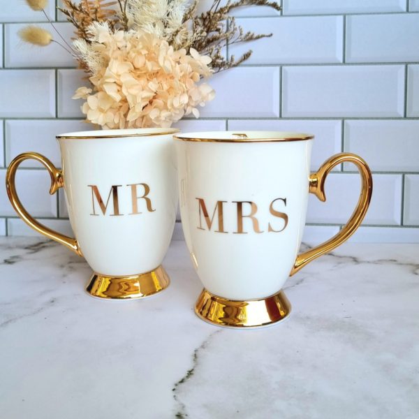 Critina Re MR and MRS mug displayed on marble table with dried flower arrangment to decorate