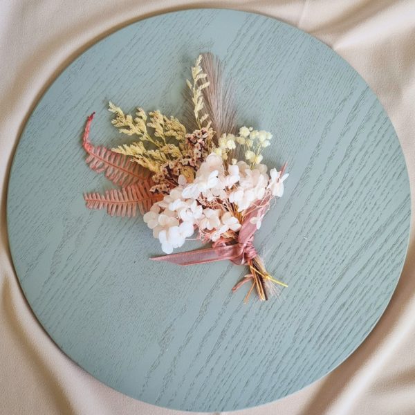 dried floral posey arranged on grey plate atop a soft pink background