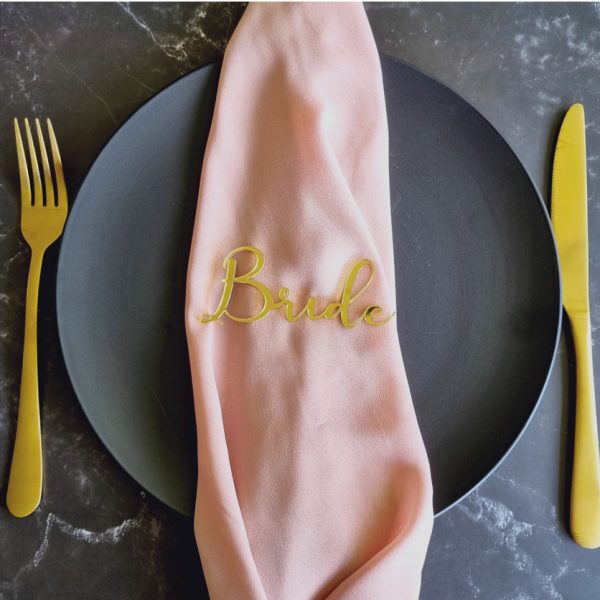 Bride acrylic name place card in mirror gold displayed on black plate with pink napkin and gold cutlery