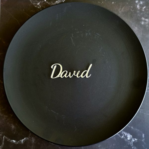 "David" name place card in mirror gold displayed on black plate on marble table
