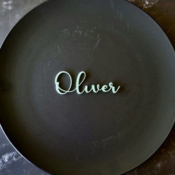 "Oliver" name place card in mint displayed on black plate on marble table