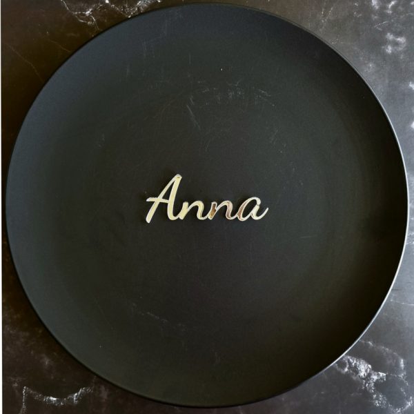 "Anna" name place card in mirror gold displayed on black plate on marble table