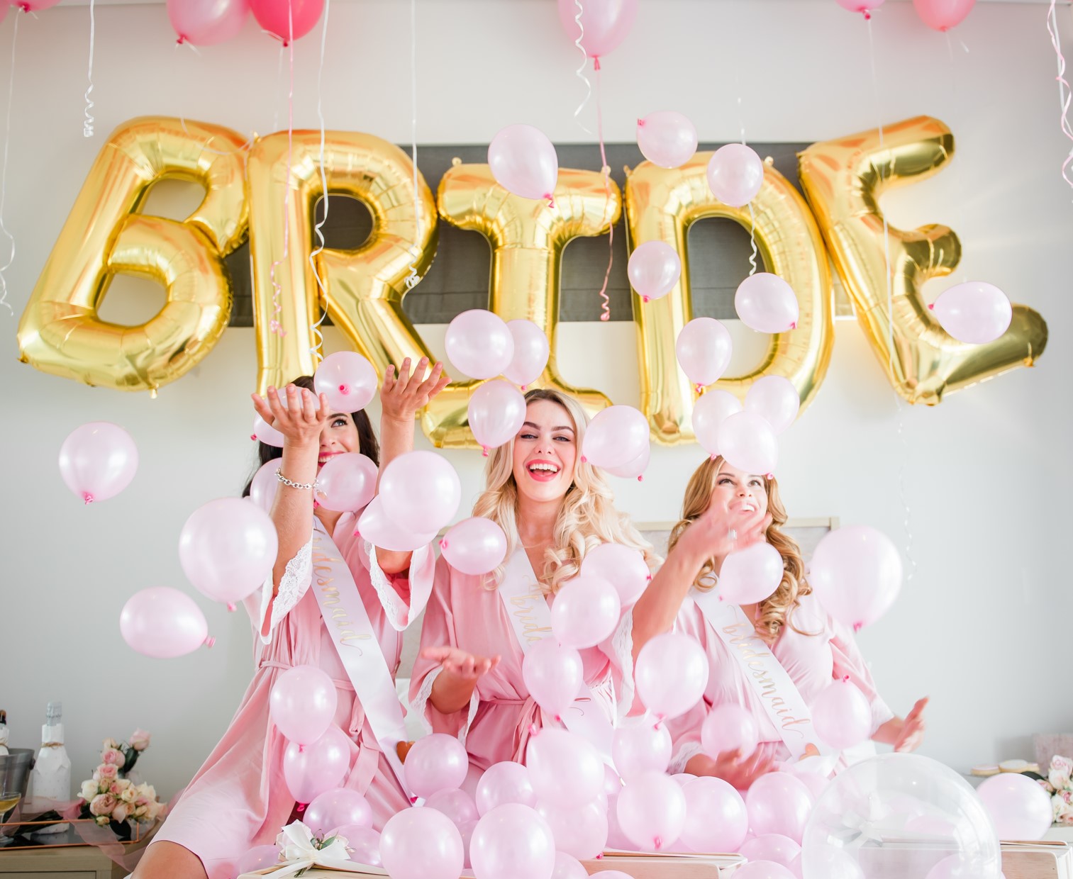 Bride and her bridesmaid throwing pink balloons around happily at bridal shower/hens party