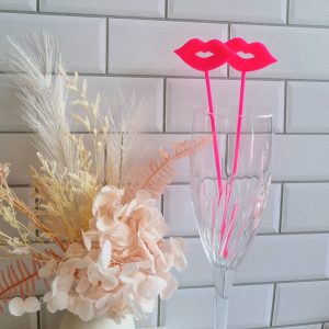 Hot pink kiss lips cocktail or mocktail stirrer in champagne glass
