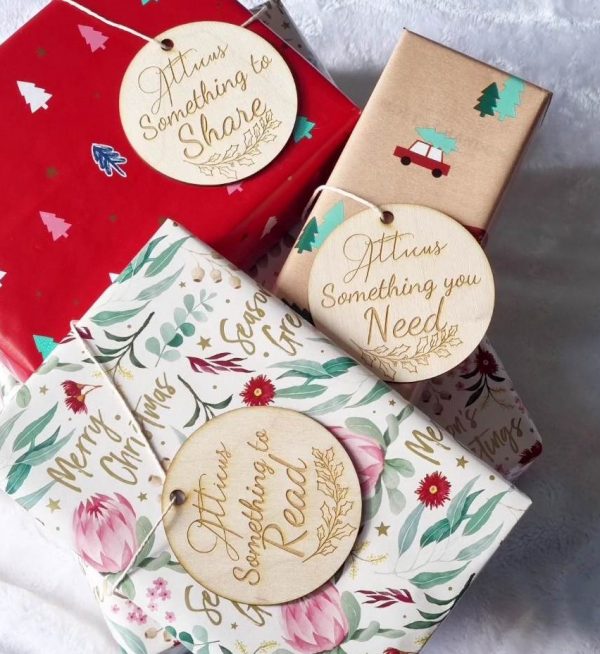 set of wooden gift tags that read "Atticus something to share, Something you need and something to read" tied to separate colourfully wrapped gifts