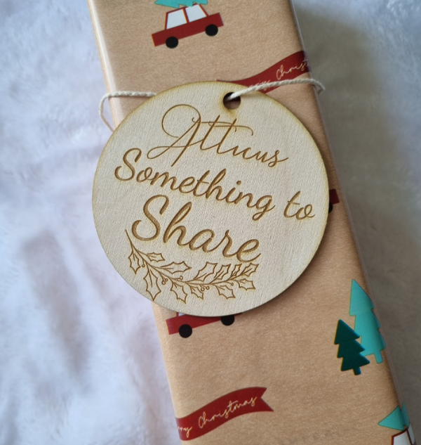 wooden gift tag tied to a christmas paper wrapped gift that reads "Atticus something to share"