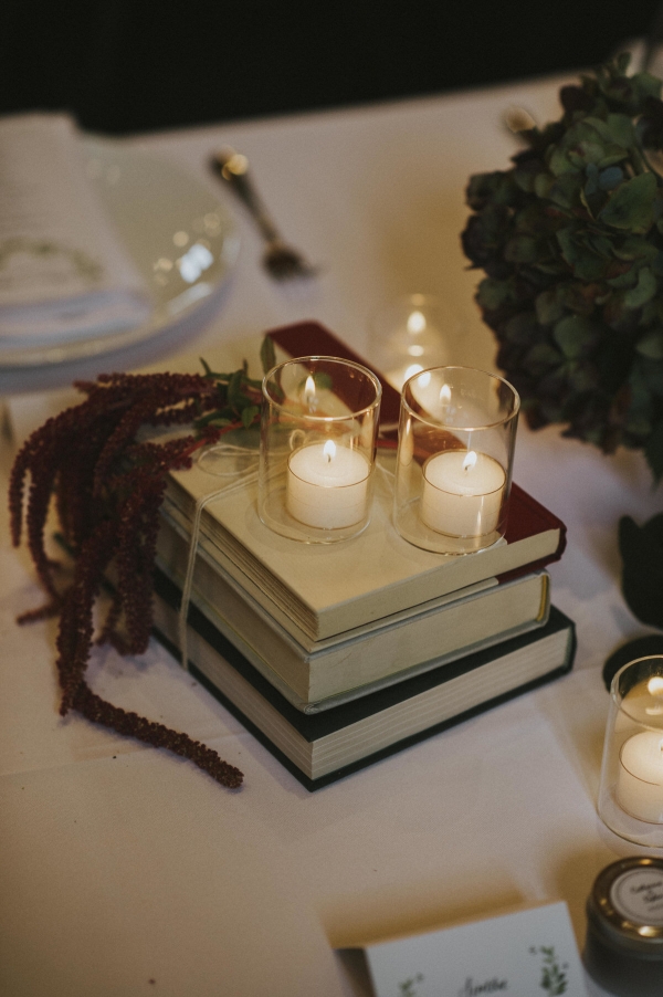 Books in a pile, with dried flowers and candles assembled as a cute table centerpiece