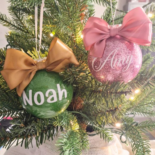 one green and one pink christmas bauble with names on the front