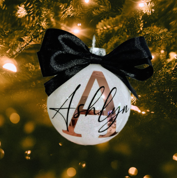 white glitter bauble with rose gold initial and black writing with a black bow on top